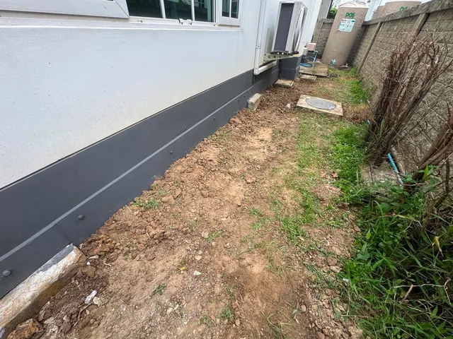 แนวโพรงใต้ผนังบ้านปิดด้วยแผ่นสีเทาเข้มยาวตลอดแนว